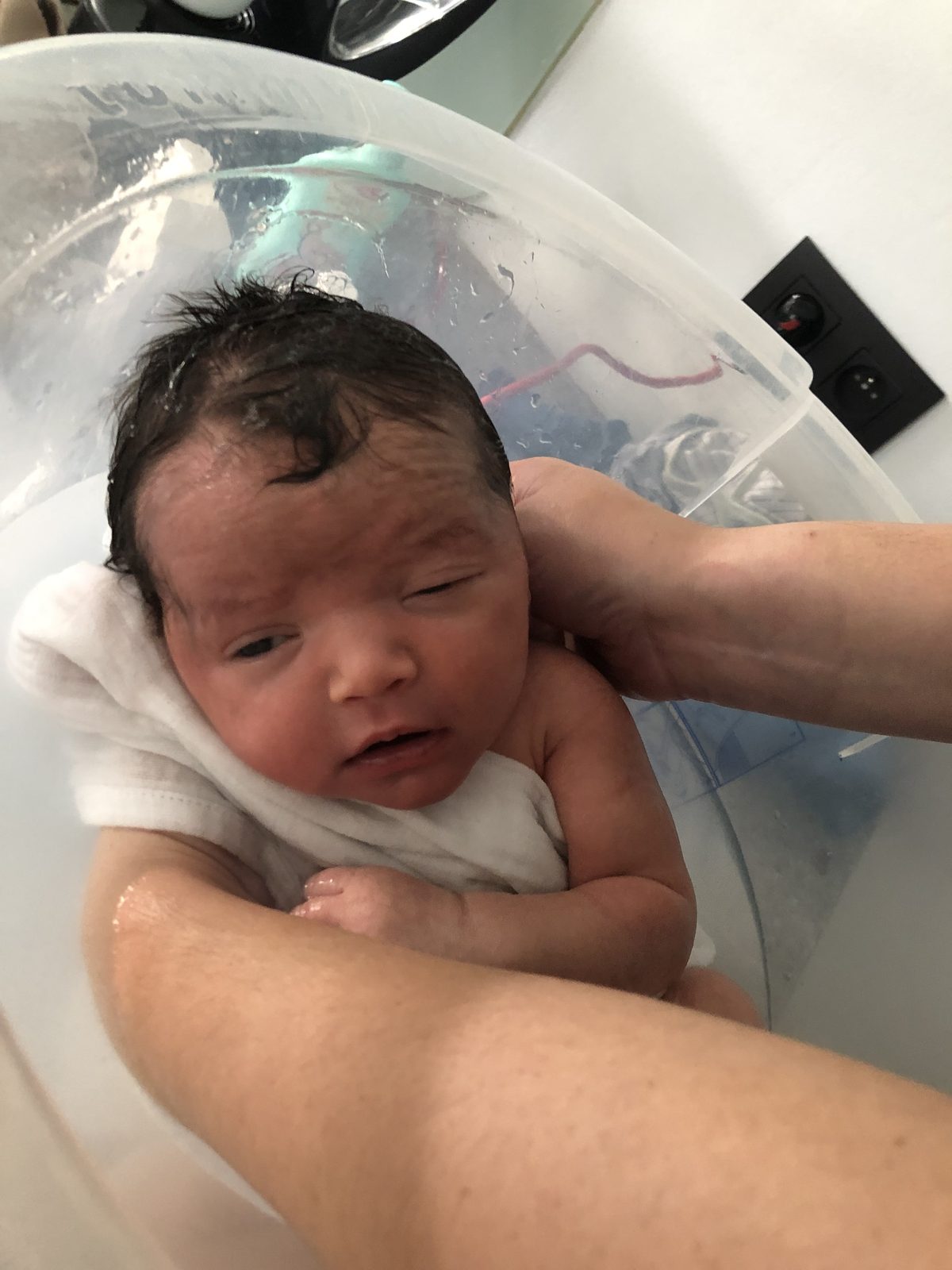 Baby wordt voorzichtig in bad ondersteund