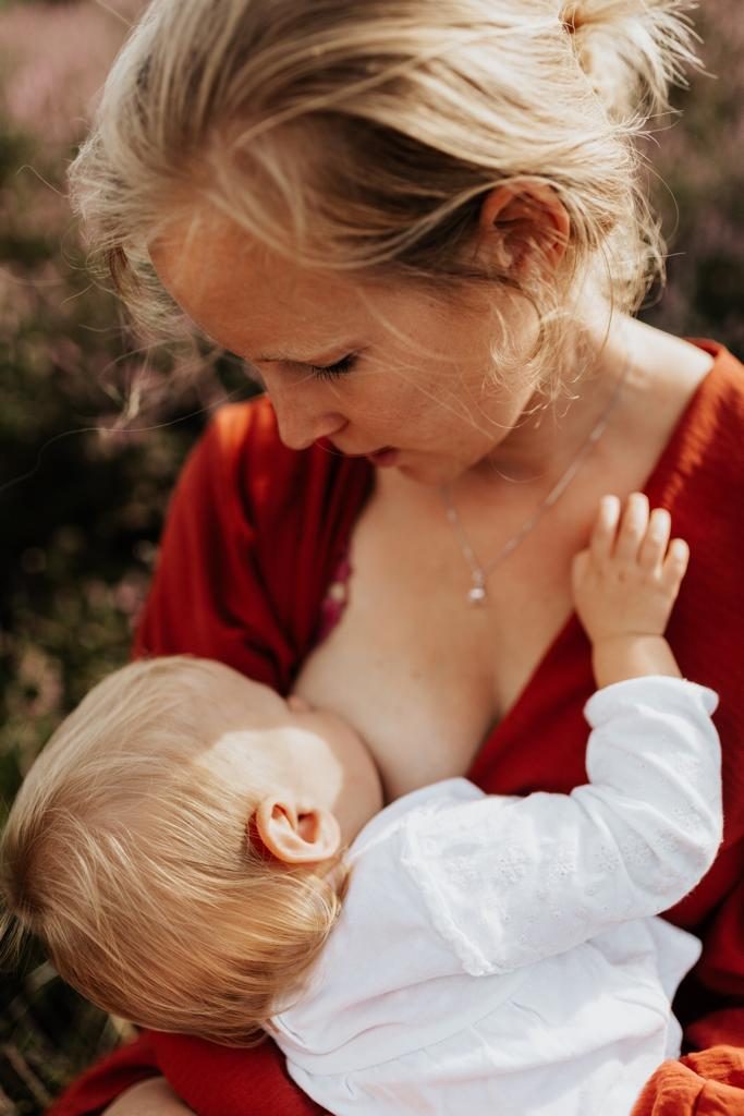 Mama geeft borstvoeding buiten in de heide