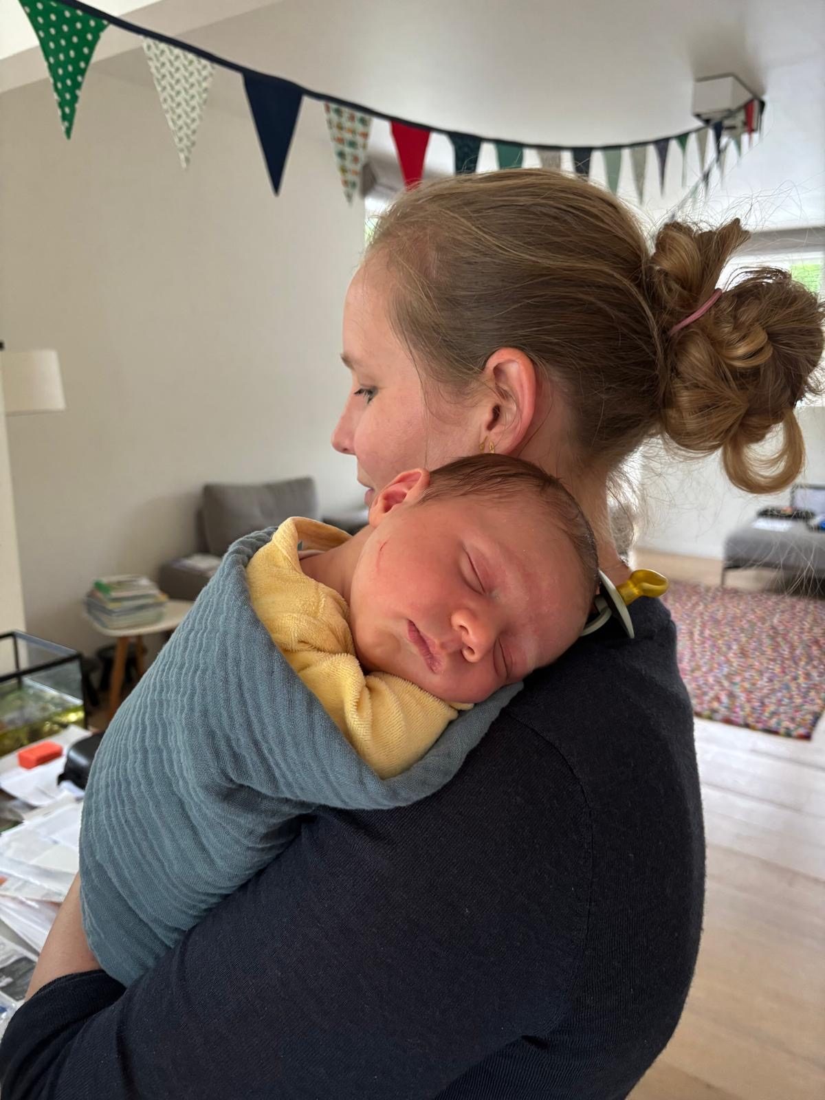 Mama met haar baby op de schouder, thuis